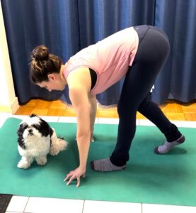 With weight in her forward foot and hands gently touching the floor in front of her, Sasha is flossing her hamstring by slightly bending and straightening her other knee to get a stretch.